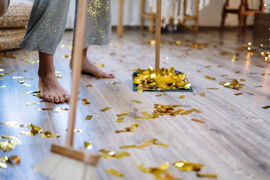 A woman is wrapping a sofa in plastic before moving it in a bright living room.